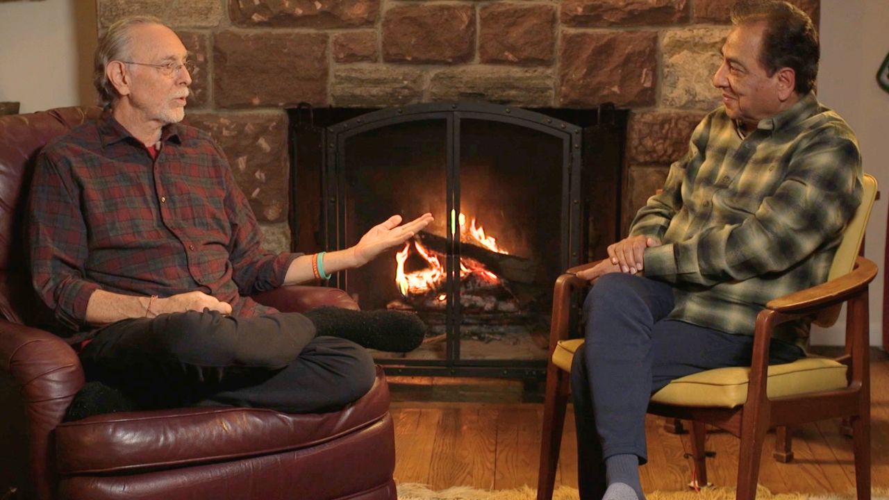 Krishna Das and Dr. Nirmal Mungali beside the fire, mid-conversation